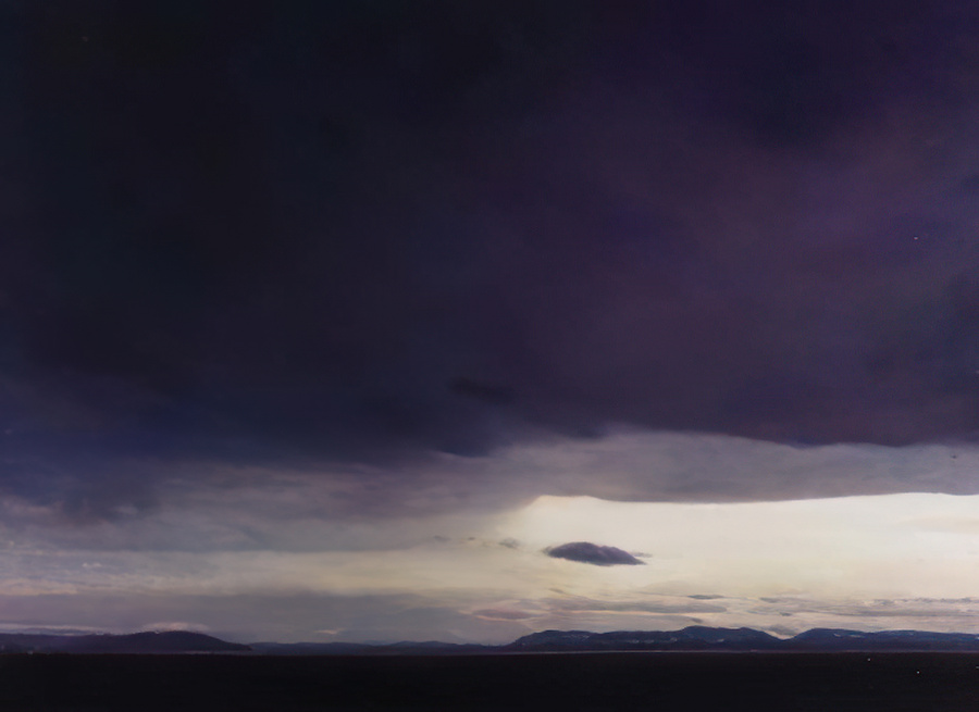 An oil painting of a break in the clouds over the Salish Sea.